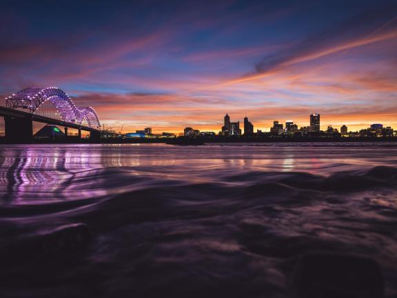 Hernando de Soto bridge over the Mississippi River at sunset with the Memphis Skyline in the background.