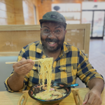 photo of Wesley smiling and holding up ramen noodles