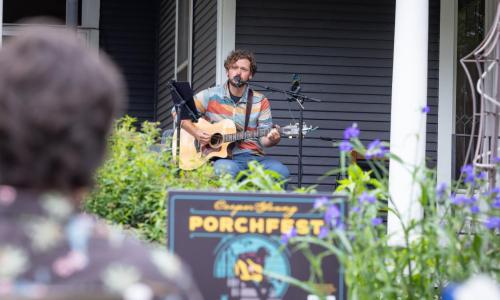 a man singing with a guitar on a porch