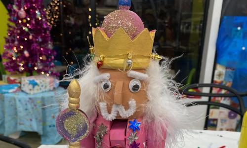 nutcracker with white hair, gold crown, and glittery pink everything else