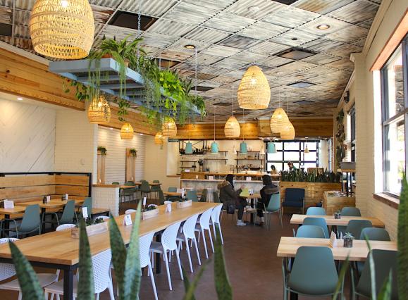 restaurant interior with warm lighting, long tables, hanging woven lamps