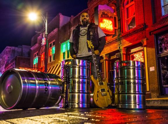 man standing behind several shiny silver kegs stacked up, Beale Street is visible in the Background
