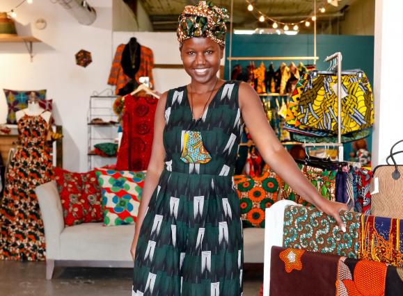owner of mbabazi shop posing in a green and black dress in the shop