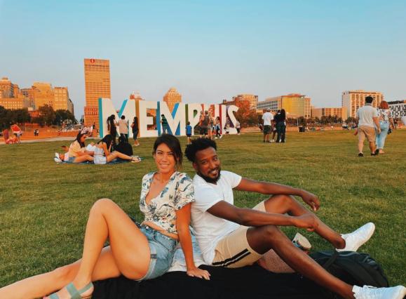 man and woman sitting in front of the MEMPHIS sign at mud island in a field