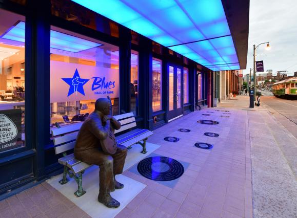 view of Blues Hall of Fame exterior with blue lights and Little Milton Statue