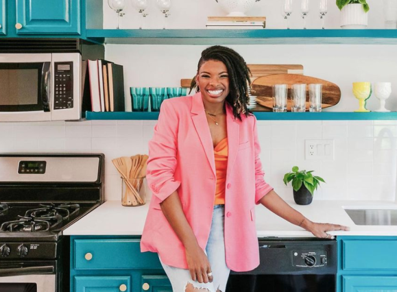 woman in colorful kitchen wearing pink blazer