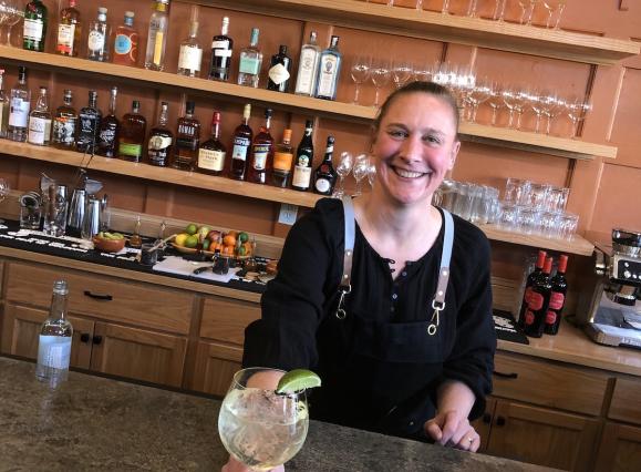 bartender holding out drink at bar