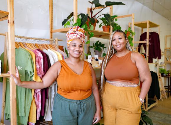 Two women in warm toned tops standing in a plant and gift shop