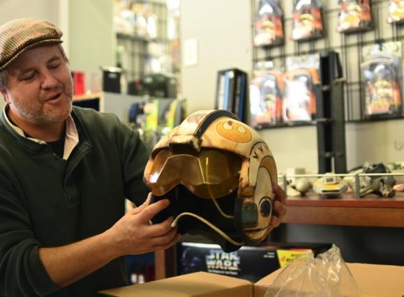 shop owner holding a vintage Star Wars character helmet