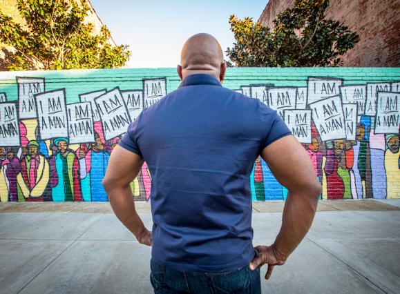man facing the I AM Man Mural 