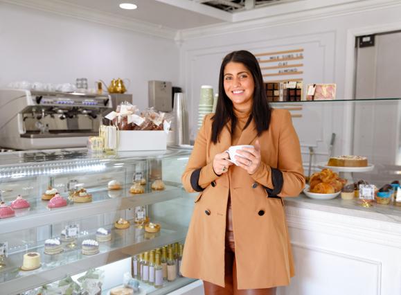 Owner of 17 Berkshire stands in front of treats display case smiling for photo