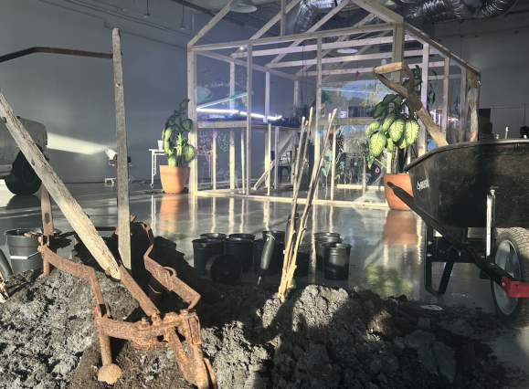 Photo of inside tone showing the brick x brick activation. There is first on the ground with shovels and the outline of a greenhouse in the background