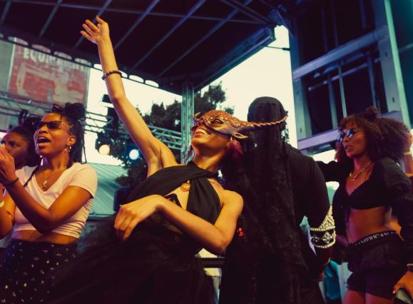 A group dancing and cheering on performers at Tone Juneteenth Gala