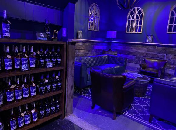 speakeasy styled tasting room at blue note bourbon bottles on shelves for sale with lounge area