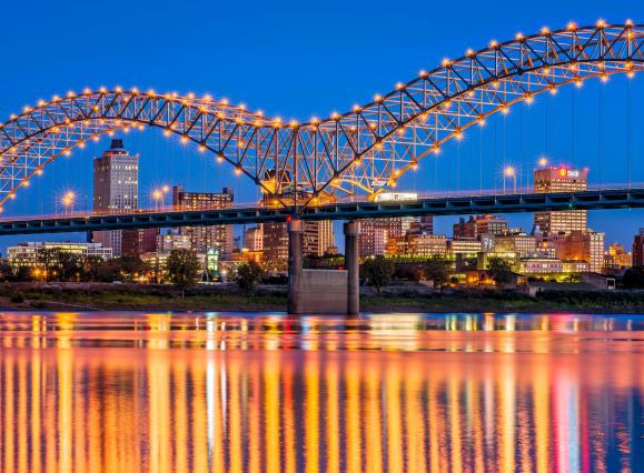 Skyline shot of downtown Memphis behind lit up bridge