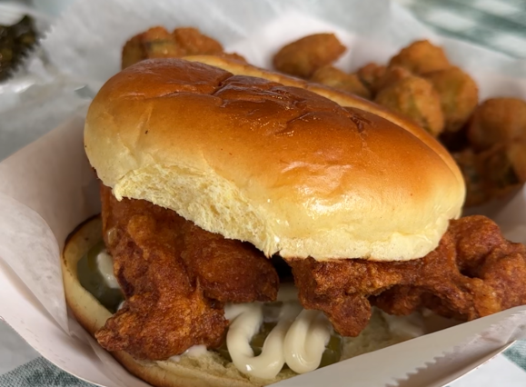 fried chicken sandwich in plate on top of green and white tablecloth