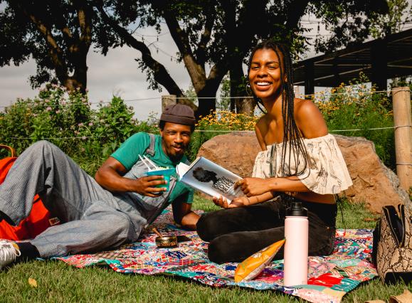 A couple reads and enjoys a picnic at River Garden Park Summer
