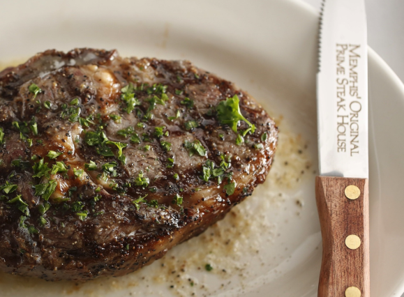well seasoned steak on plate next to steak knife