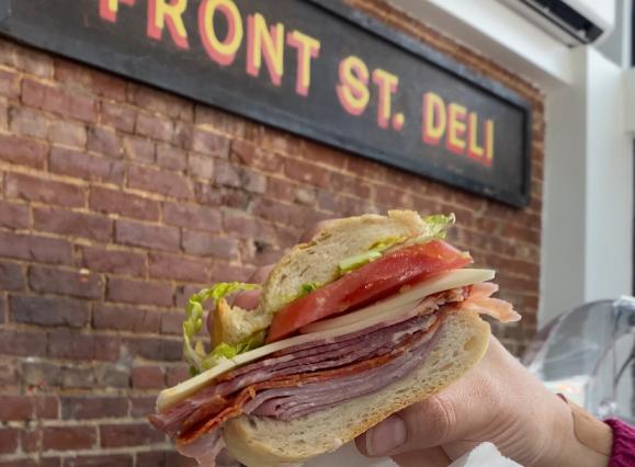 italiano sub held up to sign of Front St Deli