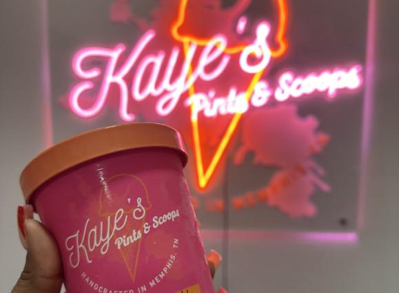 holding carrot spice cake in front of neon sign