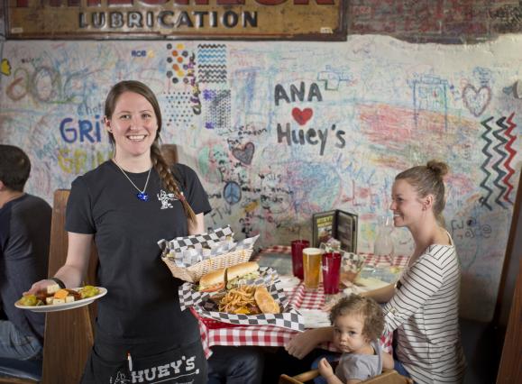 server holding food smiles for photo next to table