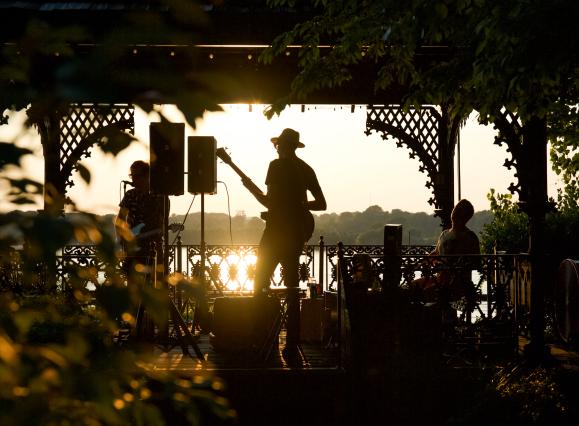 band plays on gazebo with sunset background