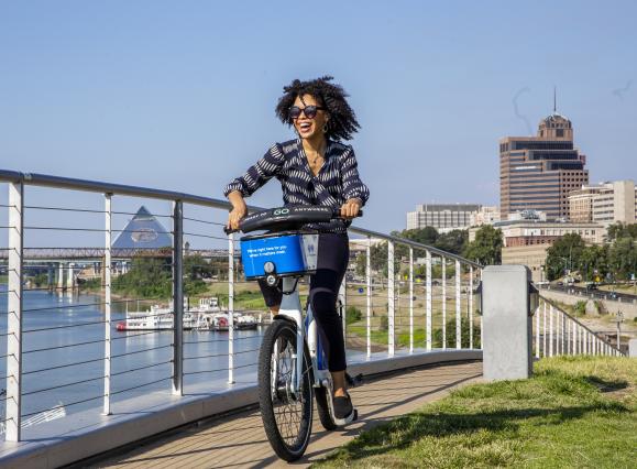 woman rides along riverfront on bike