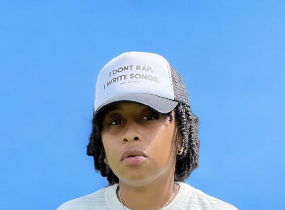 portrait of artist jus Bentley who wears a hat saying "I don't rap. I write songs."