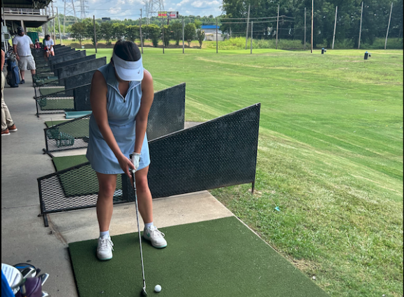 woman lines up to hit ball at driving range