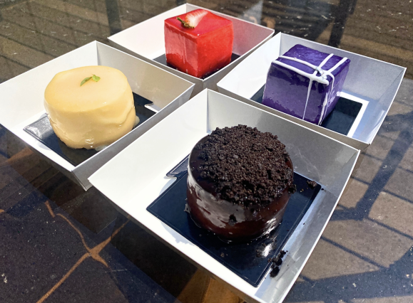 four mini cheesecakes decorated in different colors, shapes, and designs