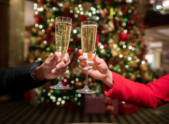 woman and man holding champagne glasses by Christmas tree