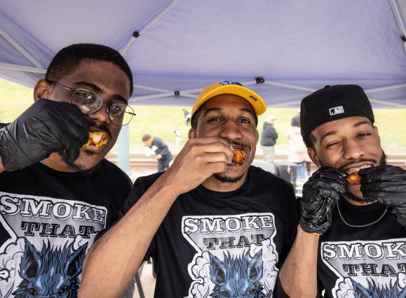 three men pose for photo eating hot wings