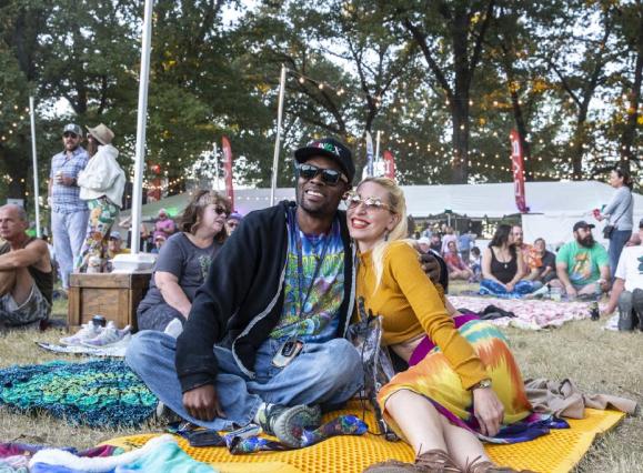A couple sitting on a blanket enjoying a performance at Mempho Music Fest with others sitting around them. 