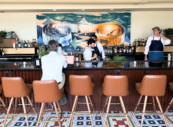 Man sits at bar at Bar Liminia while bartenders work behind it