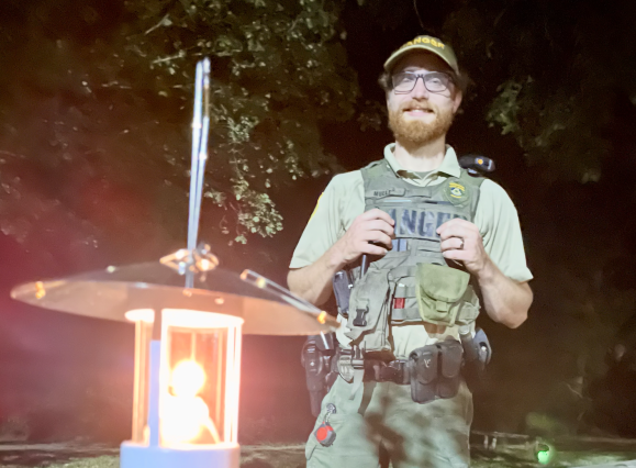 ranger smiles for photo with lantern lit in front of him