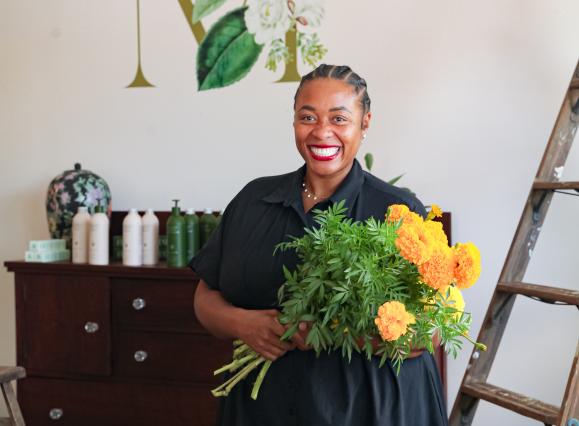 the band wilding owner smiles for photo holding yellow flowers