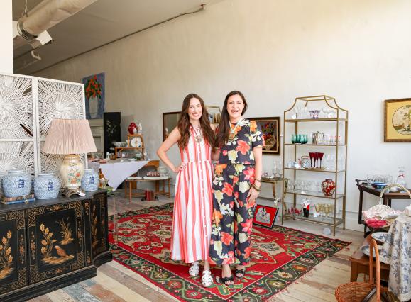 Two women standing next to each other surrounded by antiques