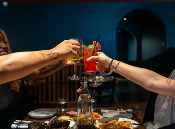 Friends raising glasses, we just see arms extended with glasses cheersing