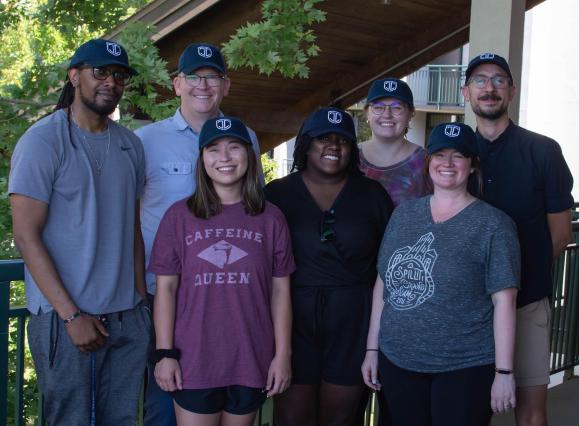 a group of people standing together smiling wearing matching navy baseball caps