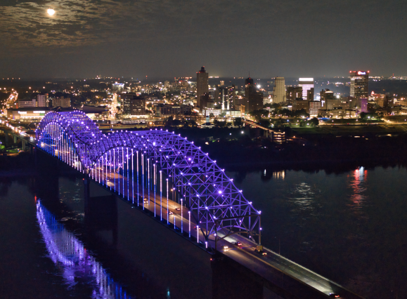 Memphis bridge lit up purple with city skyline in background