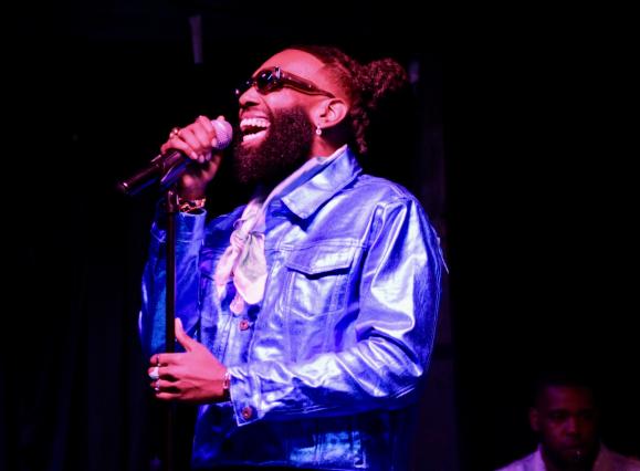 black man singing in a metallic purple jacket