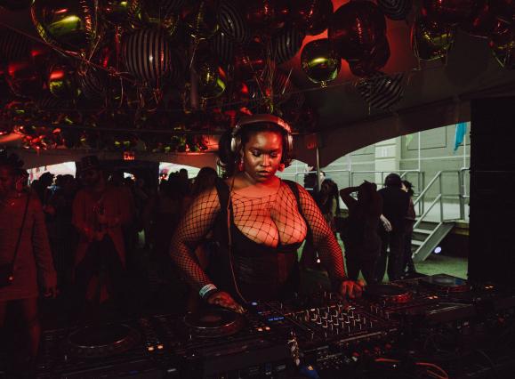 African American Woman Djing, wearing headphones with black fishnext top and black corset