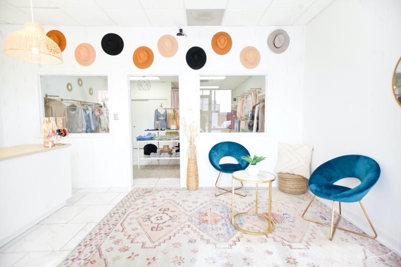 brightly lit shop lobby with teal plush chairs and wide-brimmed hats hung on the wall
