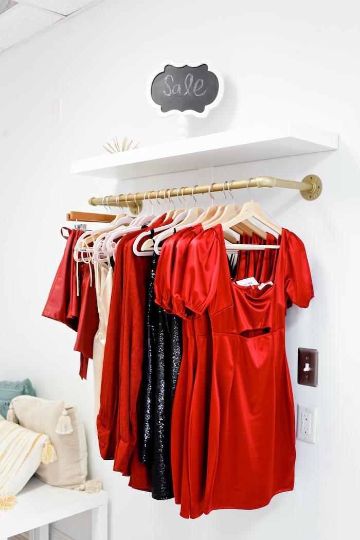 silky red and black dresses hung up under a Sale sign in a boutique