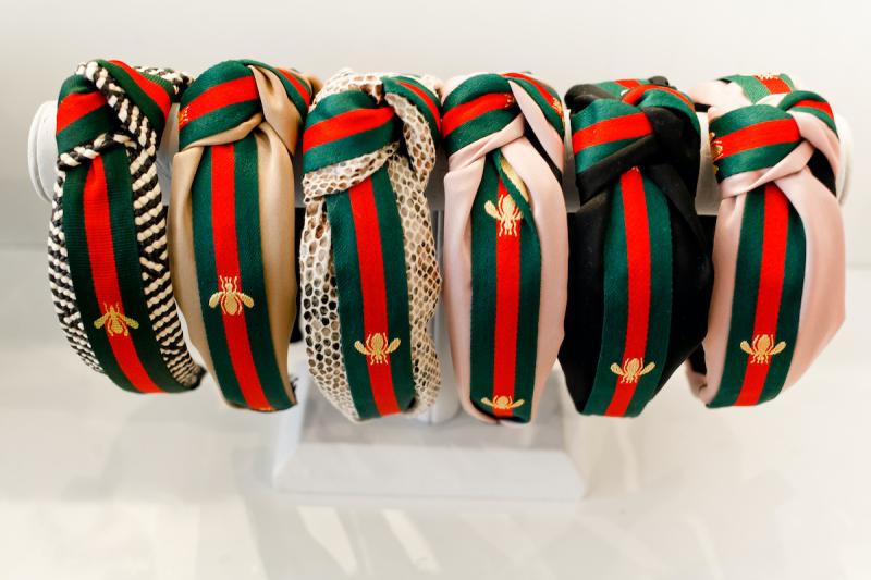 row of plush green and red ribbon headbands on a display rack