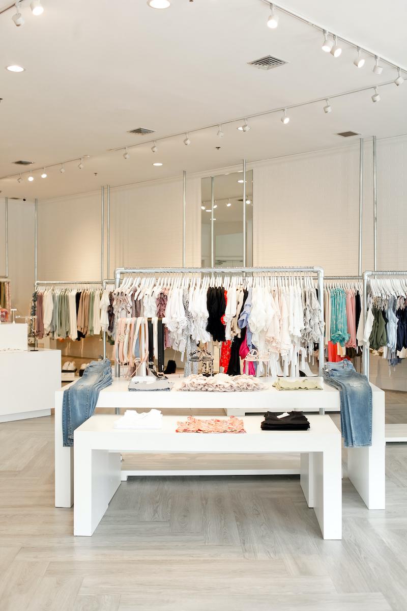 bright clothing boutique with white walls and clothes on hangers