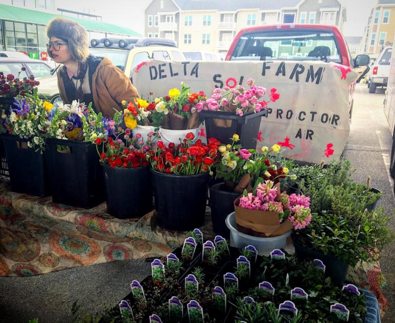farmers market booth with buckets of flowers