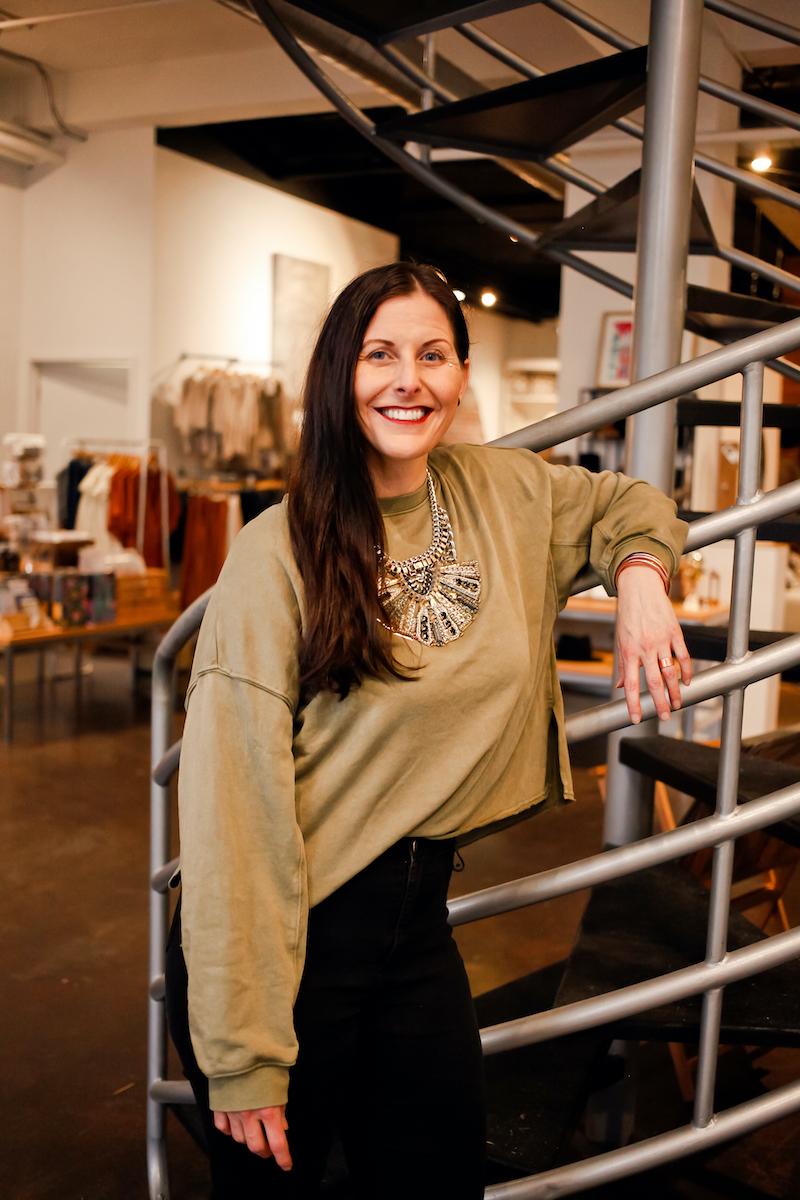 Portrait of Erika leaning on spiral staircase, in a tan sweater