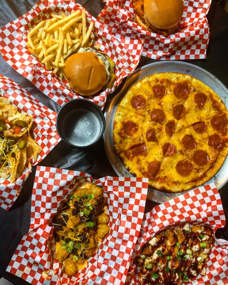 spread of food at the Hi tone including a pizza, loaded tater tots, burger and fries