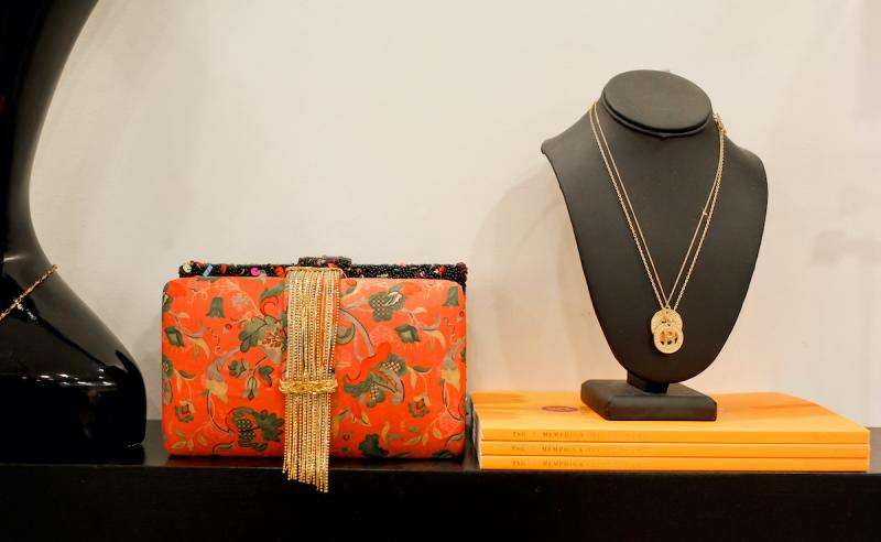 red patterned clutch and silver necklace on a stand